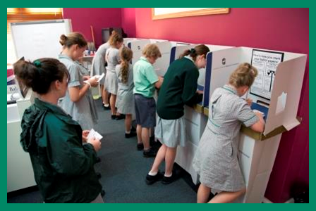 Students queuing and voting at voting screens.